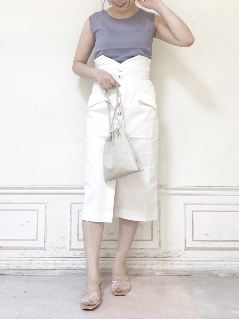 ホワイト系のデニムスカート、ホワイト系のハンドバッグ、パープル系のニット/セーターを着用したレディースの夏コーディネートの2枚目の写真