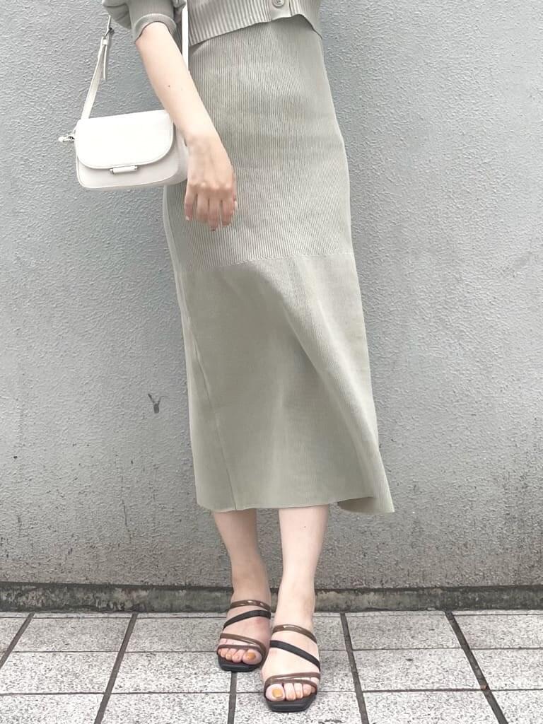 グリーン系のワンピース、ブラック系のサンダル、ホワイト系のショルダーバッグを着用したレディースの春コーディネートの3枚目の写真