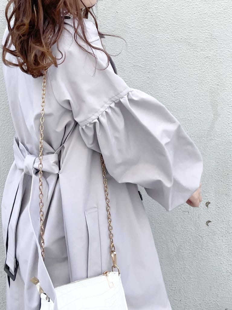 グレー系のトレンチコート、ホワイト系のワンピース、ホワイト系のパンプスを着用したレディースの冬コーディネートの4枚目の写真