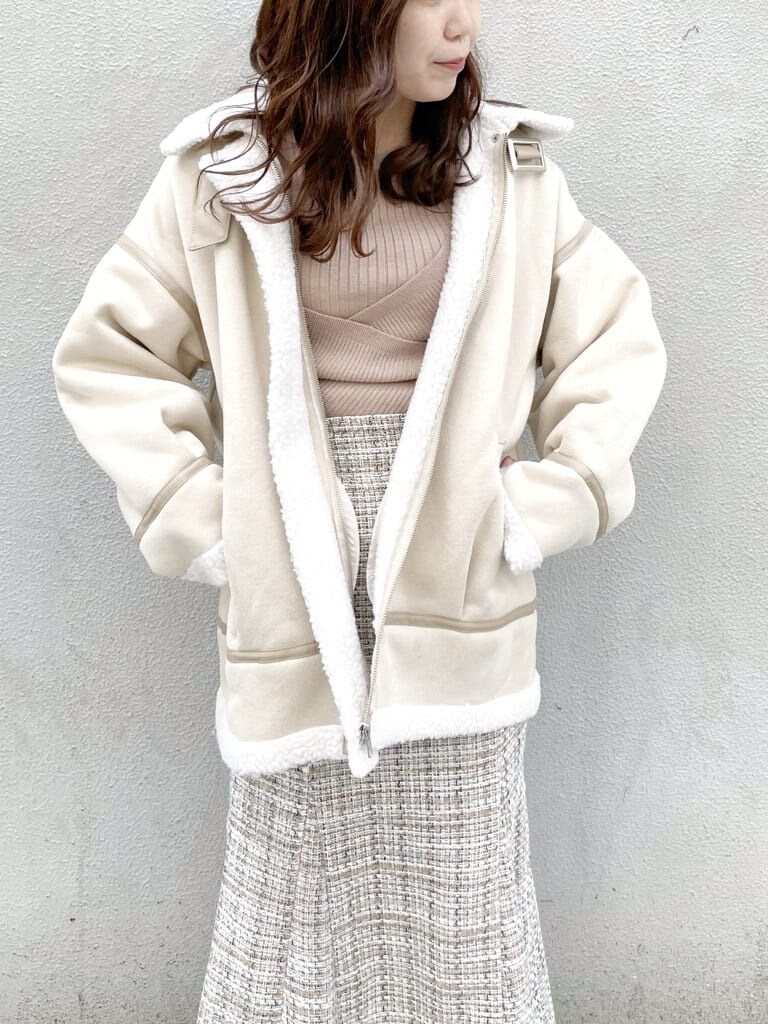 ホワイト系のブルゾン、ベージュ系のブーツ、ベージュ系のニット/セーターを着用したレディースの冬コーディネートの4枚目の写真