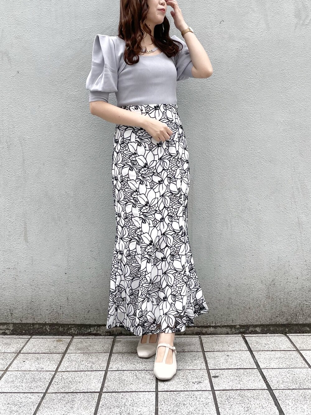 ブルー系のニット/セーター、ホワイト系のスカート、ホワイト系のパンプスを着用したレディースの春コーディネートの2枚目の写真