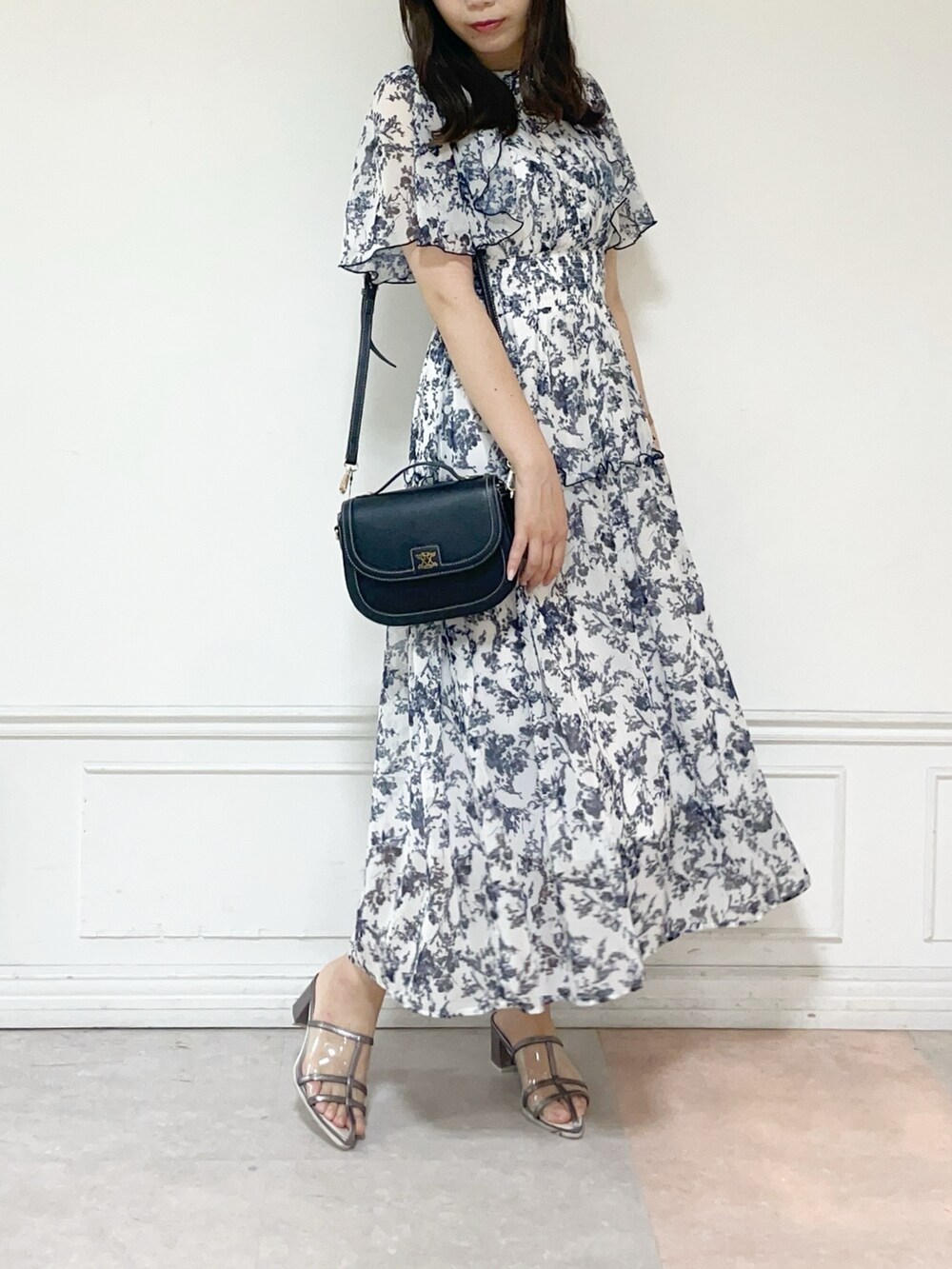 ホワイト系のワンピース、ブラック系のハンドバッグ、シルバー系のパンプスを着用したレディースの夏コーディネートの2枚目の写真