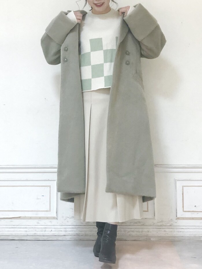 ベージュ系のスカート、グリーン系のニット/セーター、グリーン系のチェスターコートを着用したレディースの秋コーディネートの3枚目の写真