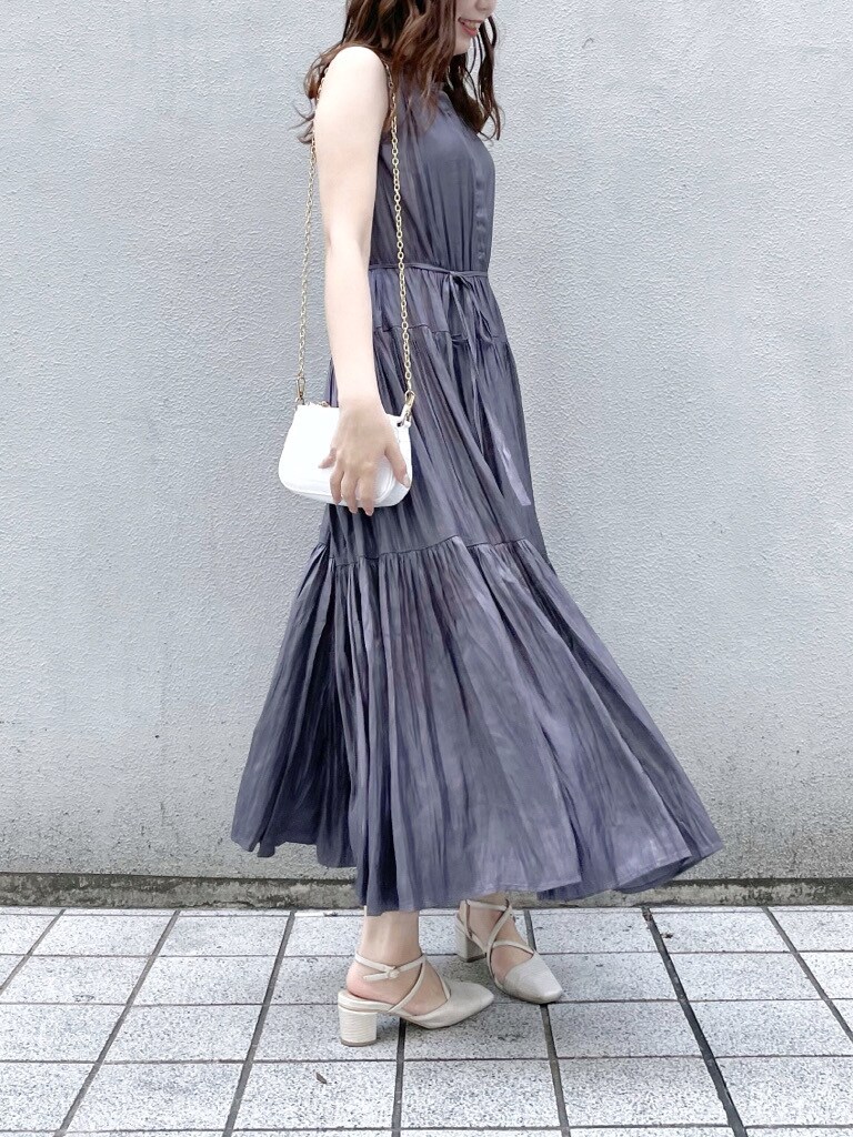 パープル系のワンピース、ホワイト系のパンプス、ホワイト系のショルダーバッグを着用したレディースの春コーディネートの2枚目の写真