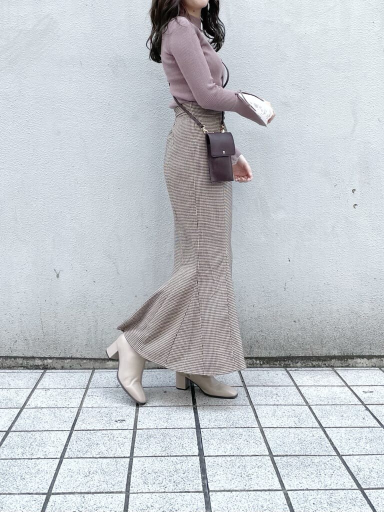 ブラウン系のスカート、ベージュ系のブーツ、ピンク系のニット/セーターを着用したレディースの秋コーディネートの2枚目の写真