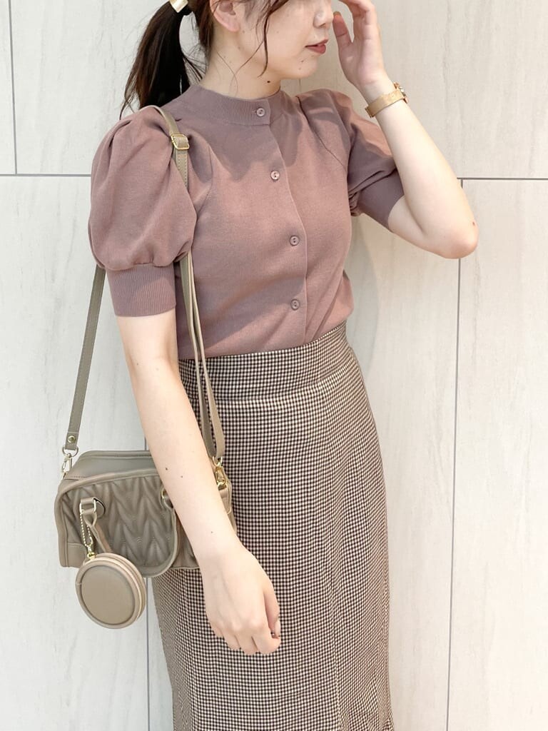 ブラウン系のスカート、ピンク系のニット/セーター、ベージュ系のハンドバッグを着用したレディースの秋コーディネートの4枚目の写真