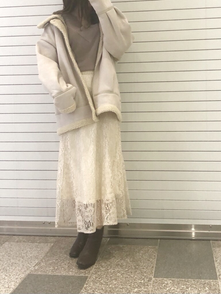 ブラウン系のブーツ、ホワイト系のスカート、ホワイト系のブルゾンを着用したレディースの冬コーディネートの2枚目の写真