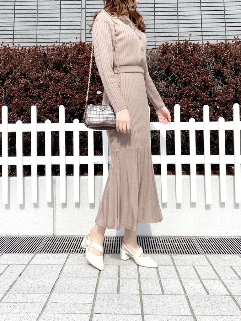 ベージュ系のワンピース、ホワイト系のパンプス、ブラウン系のショルダーバッグを着用したレディースの冬コーディネートの4枚目の写真