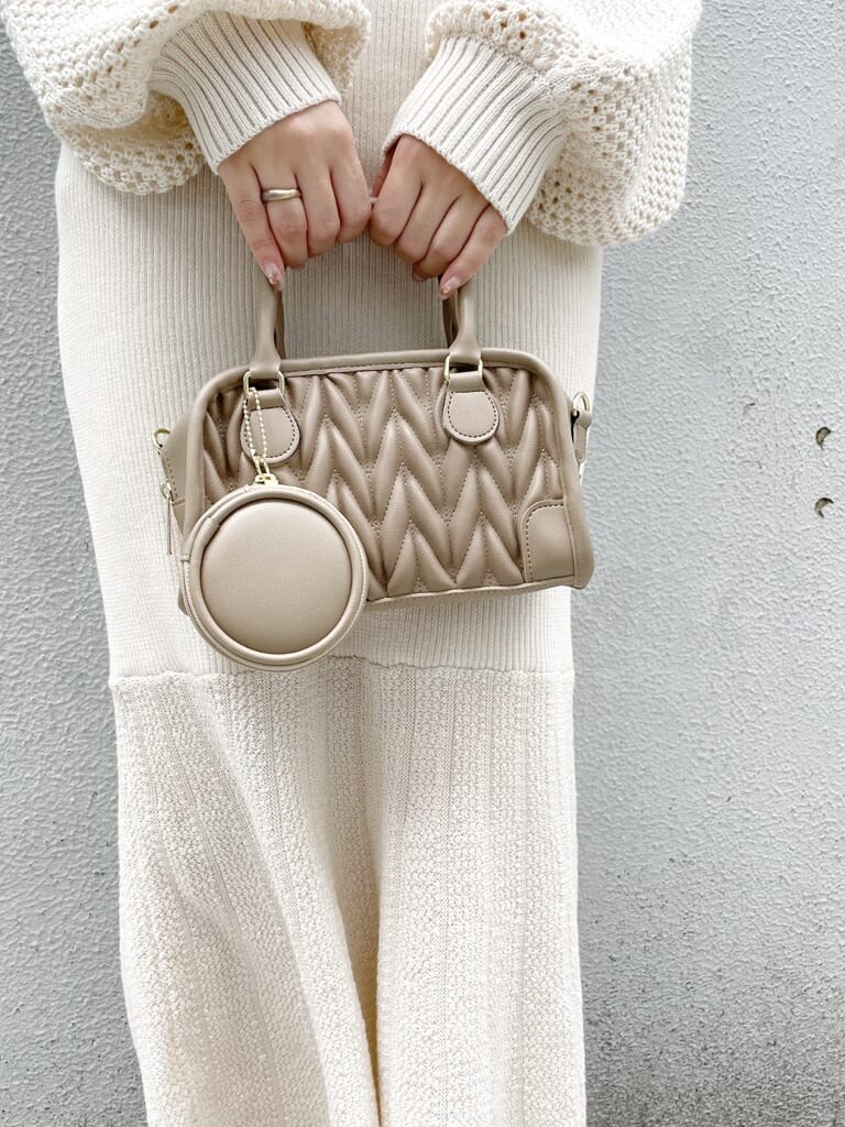 ホワイト系のワンピース、ホワイト系のパンプス、ベージュ系のハンドバッグを着用したレディースの秋コーディネートの5枚目の写真