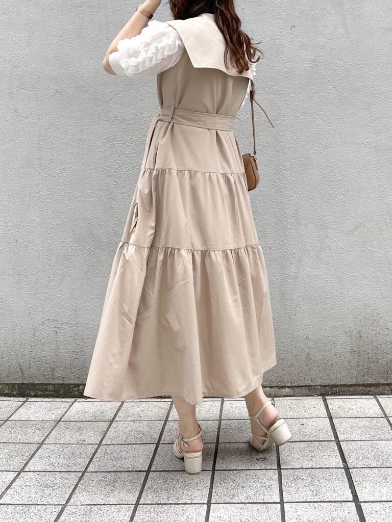 ベージュ系のワンピース、ホワイト系のパンプス、ブラウン系のショルダーバッグを着用したレディースの春コーディネートの4枚目の写真