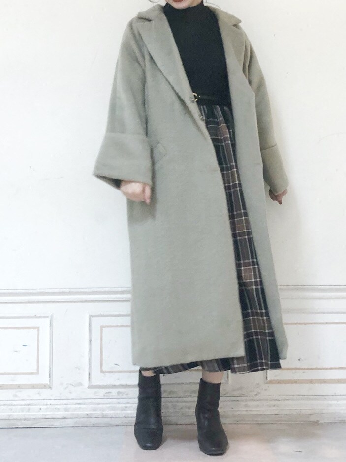 ブラウン系のブーツ、グリーン系のチェスターコート、ブラック系のワンピースを着用したレディースの秋コーディネートの2枚目の写真