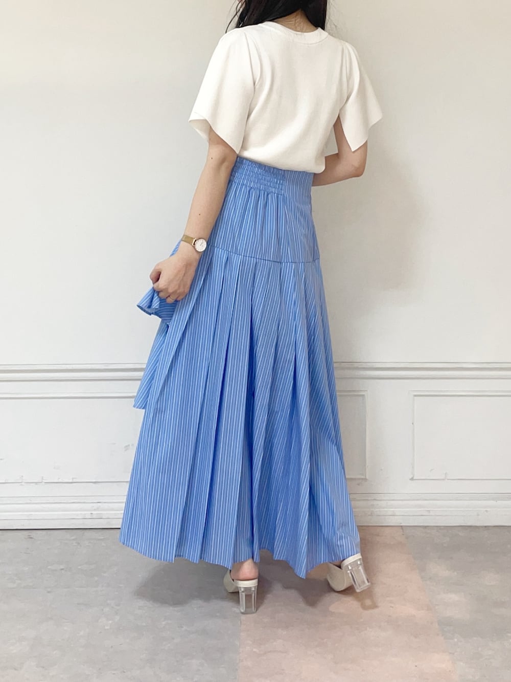 ホワイト系のニット/セーター、ブルー系のスカート、ホワイト系のパンプスを着用したレディースの春コーディネートの2枚目の写真