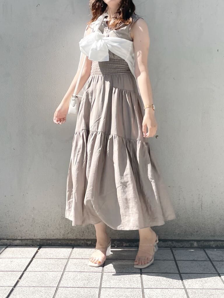 ホワイト系のショルダーバッグ、パープル系のサンダル、ベージュ系のワンピースを着用したレディースの春コーディネートの2枚目の写真