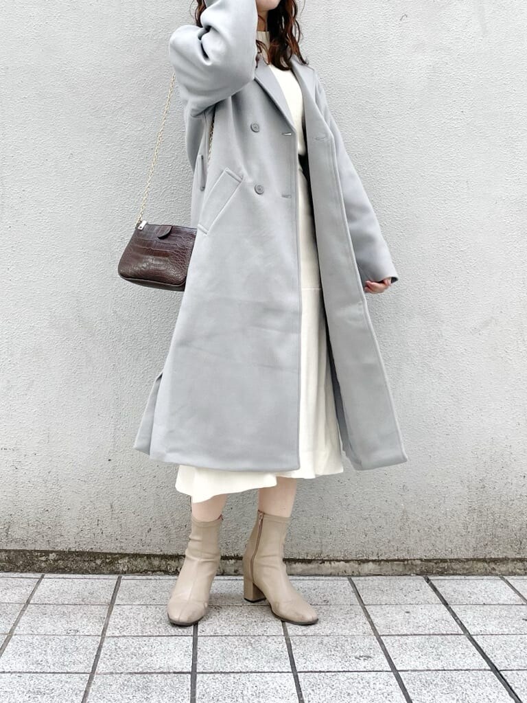 ベージュ系のブーツ、ホワイト系のワンピース、ブルー系のチェスターコートを着用したレディースの冬コーディネートの2枚目の写真