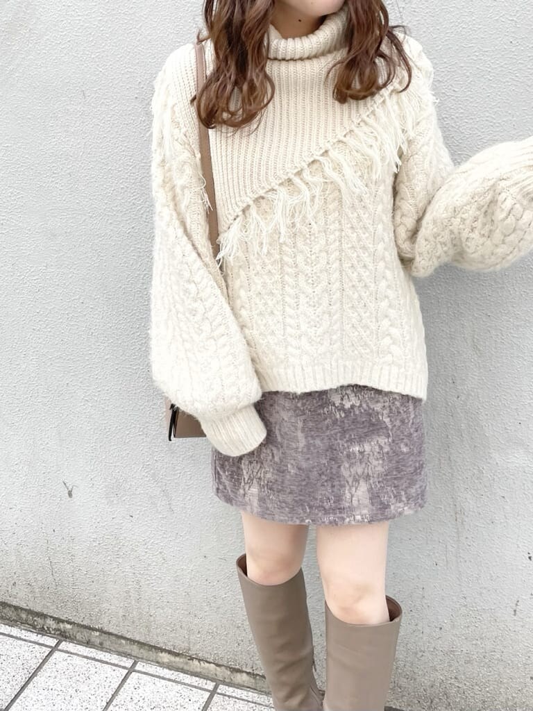 グレー系のスカート、ベージュ系のブーツ、ベージュ系のハンドバッグを着用したレディースの秋コーディネートの3枚目の写真