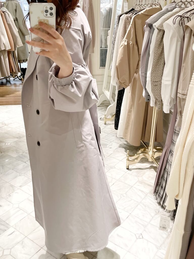 ベージュ系のブーツ、グレー系のトレンチコート、ホワイト系のワンピースを着用したレディースの冬コーディネートの2枚目の写真