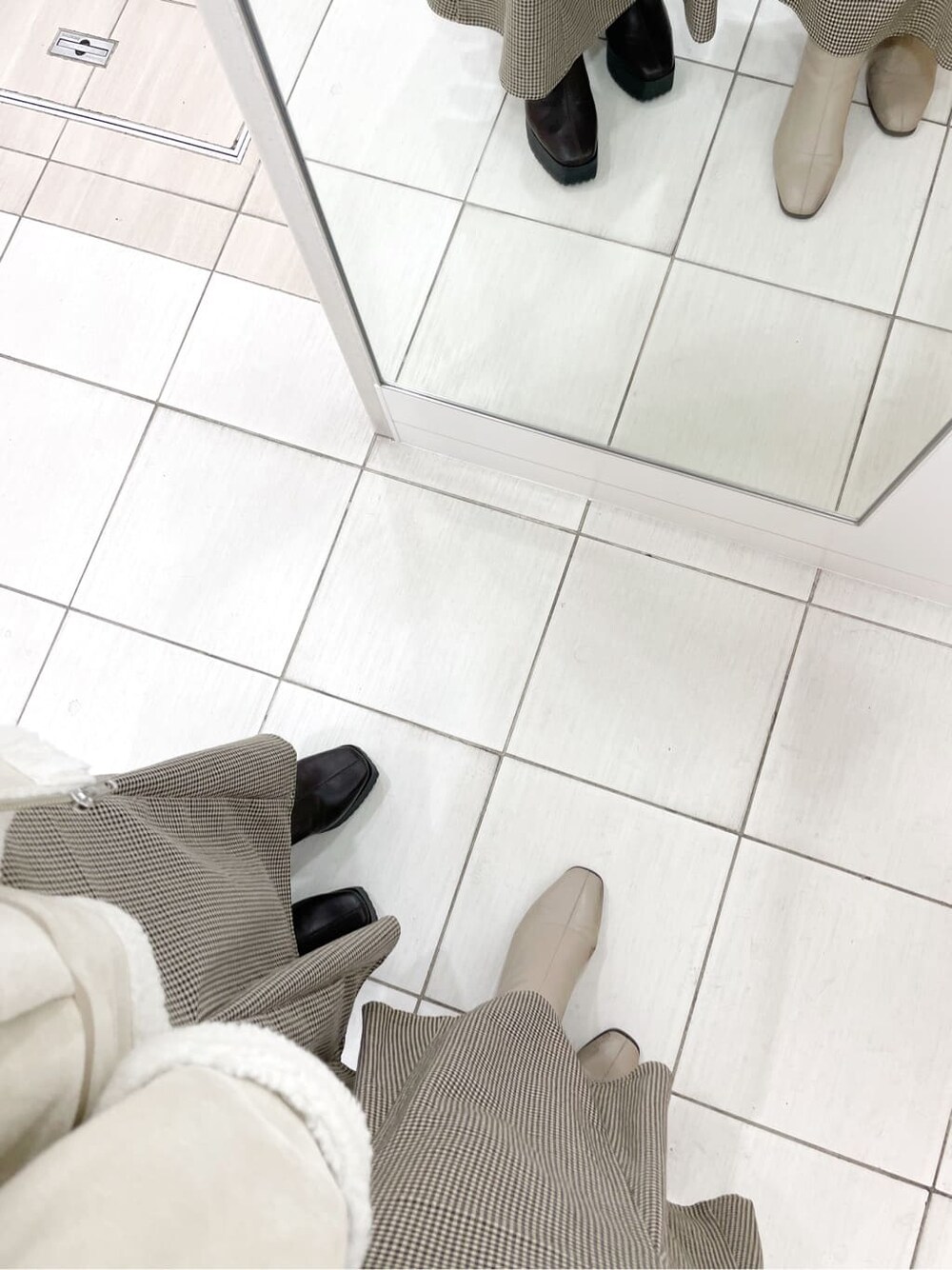 ブラウン系のスカート、ベージュ系のブーツ、ホワイト系のブルゾンを着用したレディースの冬コーディネートの3枚目の写真