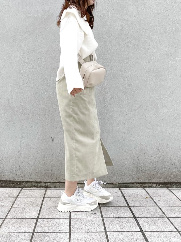 ホワイト系のスニーカー、グリーン系のスカート、ホワイト系のハンドバッグを着用したレディースの秋コーディネートの2枚目の写真