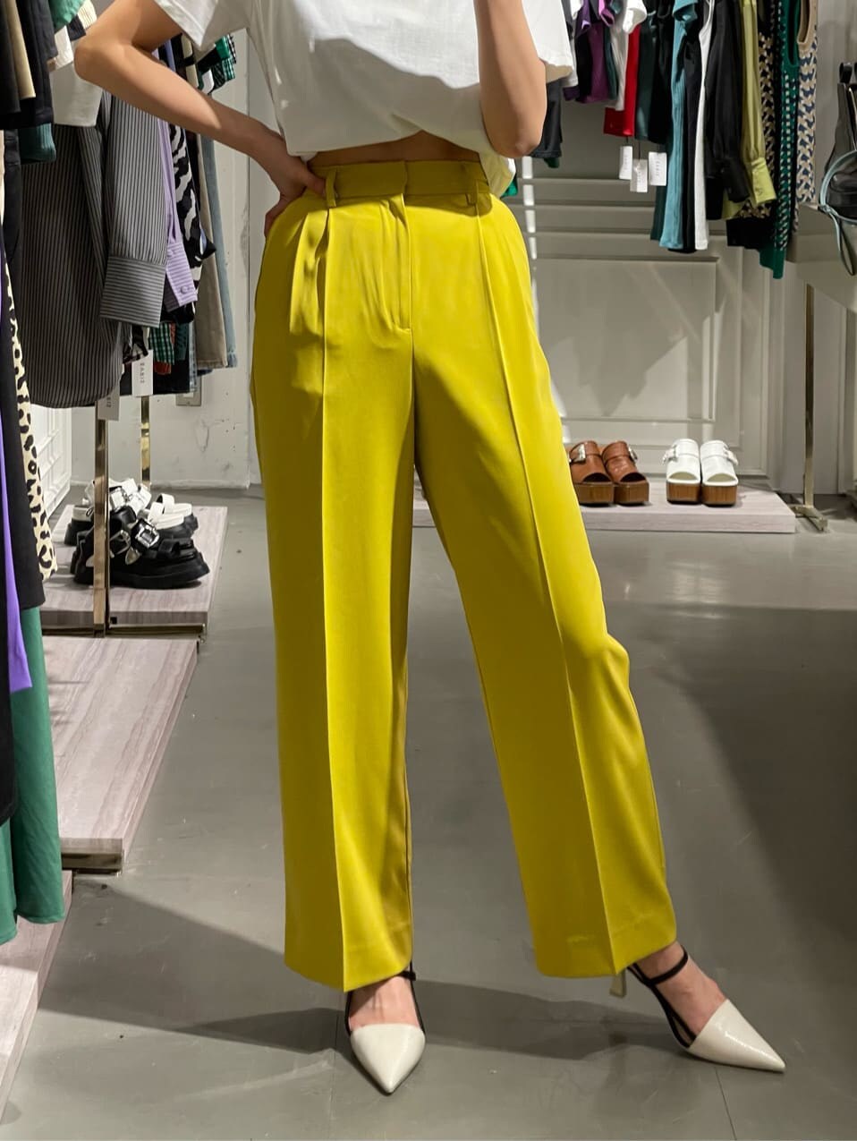 イエロー系のスラックス、ホワイト系のTシャツ/カットソー、ホワイト系のサンダルを着用したレディースの春コーディネートの4枚目の写真