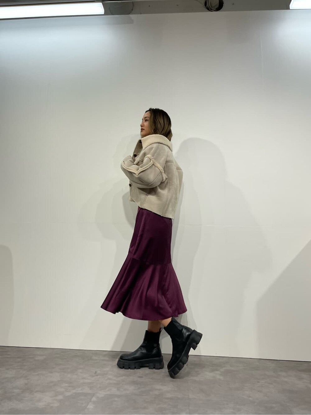 ブラック系のブーツ、ホワイト系のニット/セーター、パープル系のスカートを着用したレディースの秋コーディネートの4枚目の写真