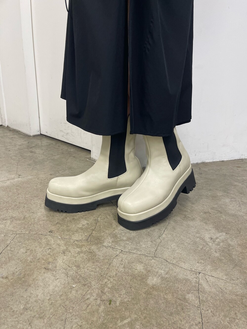 ブラック系のスカート、ホワイト系のブーツ、ブラック系のニット/セーターを着用したレディースの秋コーディネートの7枚目の写真