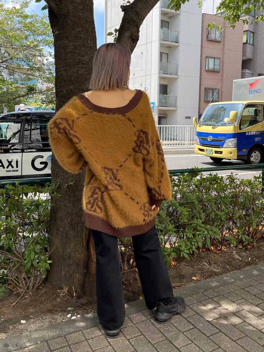 ブラック系のデニムパンツ、ブラウン系のカーディガン/ボレロ、ゴールド系のピアス（両耳用）を着用したレディースの秋コーディネートの3枚目の写真