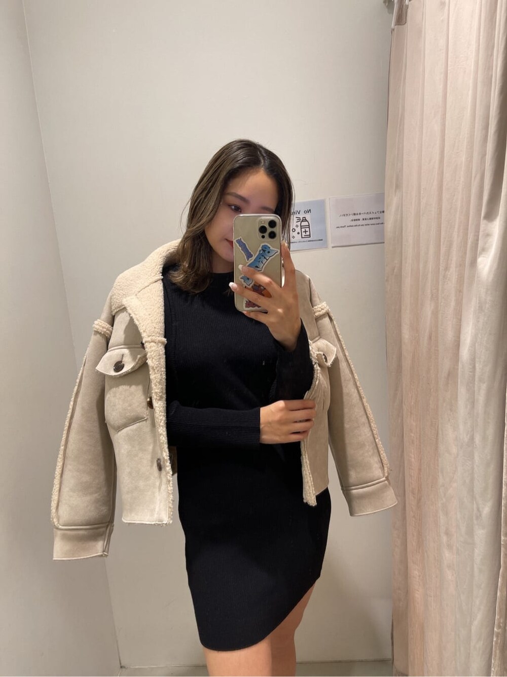 ブラック系のワンピース、ブラック系のブーツ、ホワイト系のブルゾンを着用したレディースの冬コーディネートの2枚目の写真