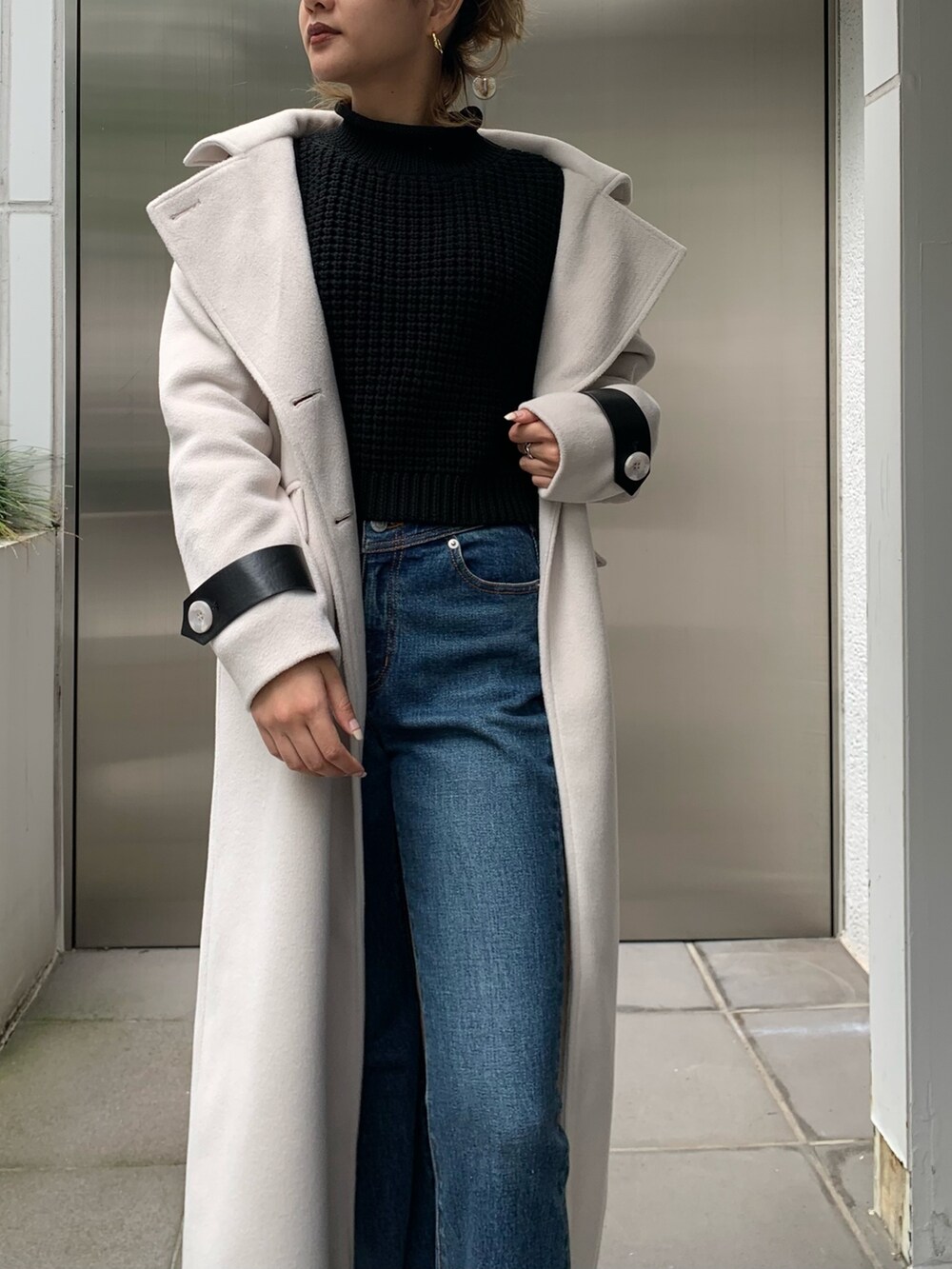 ホワイト系のその他アウター、ブラック系のニット/セーター、ブルー系のデニムパンツを着用したレディースの秋コーディネートの5枚目の写真