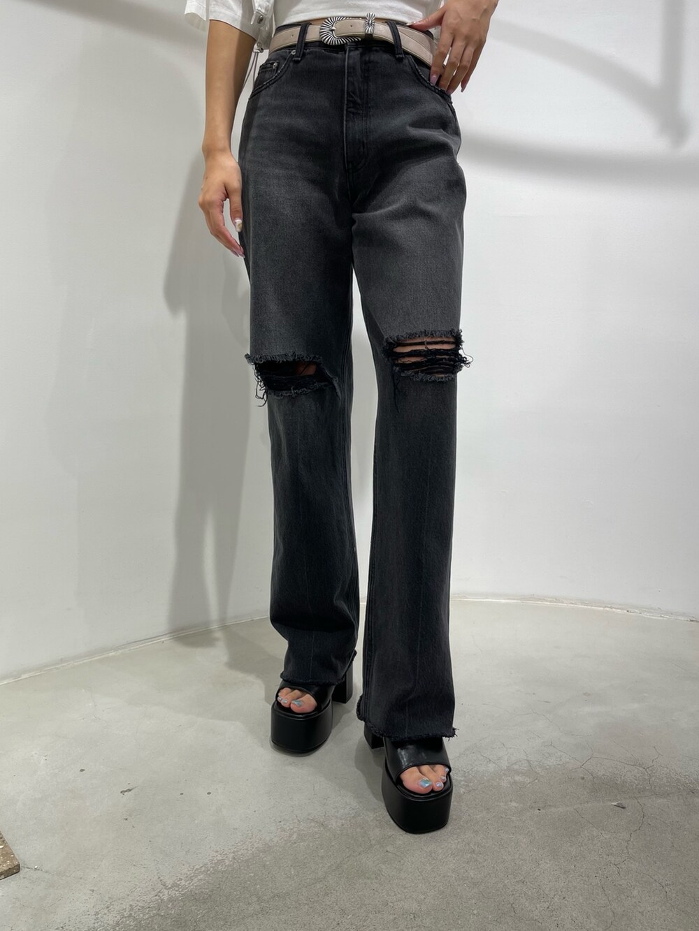 ブラック系のデニムパンツ、ブラック系のサンダル、ホワイト系のキャミソールを着用したレディースの夏コーディネートの4枚目の写真