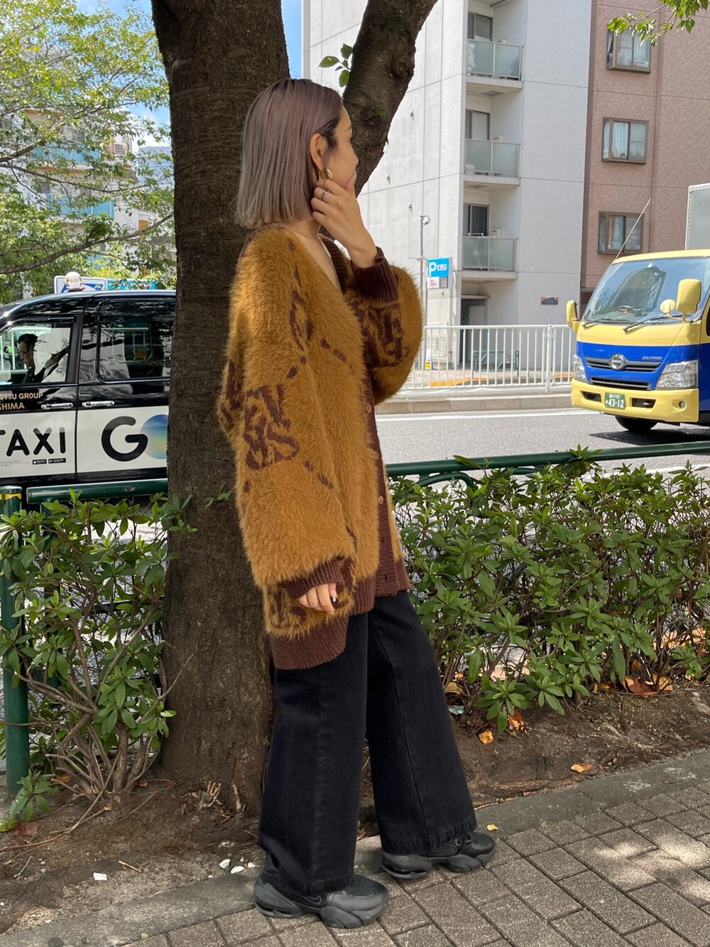 ブラック系のデニムパンツ、ブラウン系のカーディガン/ボレロ、ゴールド系のピアス（両耳用）を着用したレディースの秋コーディネートの4枚目の写真