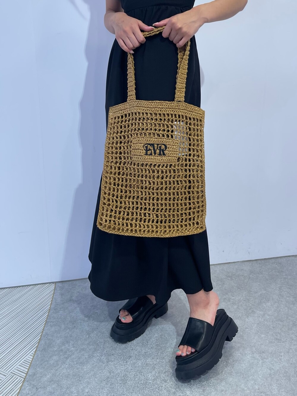 ベージュ系のトートバッグ、ブラック系のワンピース、ブラック系のサンダルを着用したレディースの夏コーディネートの7枚目の写真