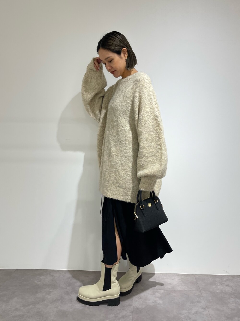 ブラック系のスカート、ホワイト系のブーツ、ブラック系のショルダーバッグを着用したレディースの秋コーディネートの3枚目の写真