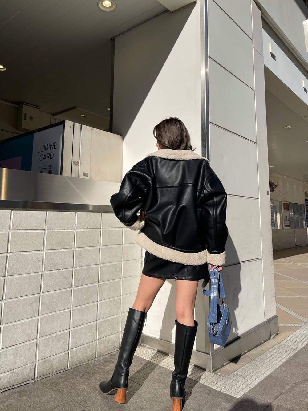 ブラック系のブルゾン、ブラック系のブーツ、ホワイト系のニット/セーターを着用したレディースの冬コーディネートの4枚目の写真