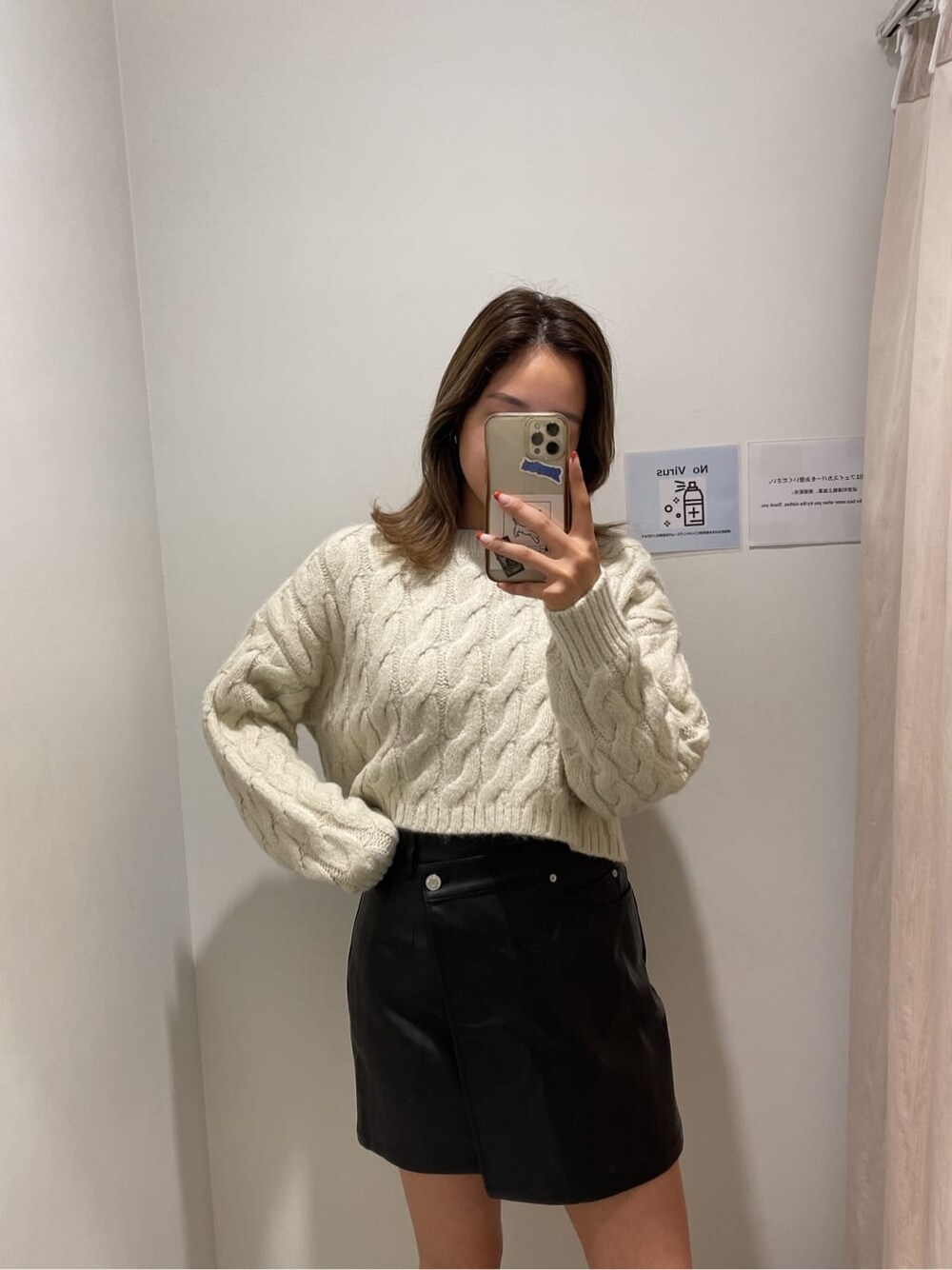 ブラック系のブーツ、ブラック系のスカート、ホワイト系のニット/セーターを着用したレディースの秋コーディネートの2枚目の写真