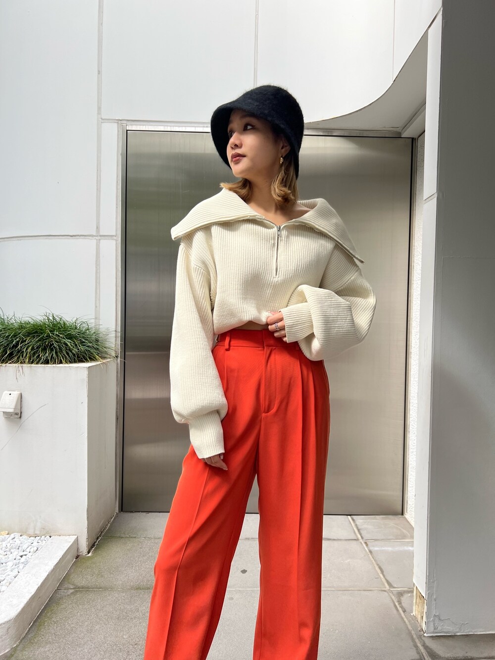 オレンジ系のスラックス、ホワイト系のニット/セーター、ブラック系のローファーを着用したレディースの秋コーディネートの5枚目の写真