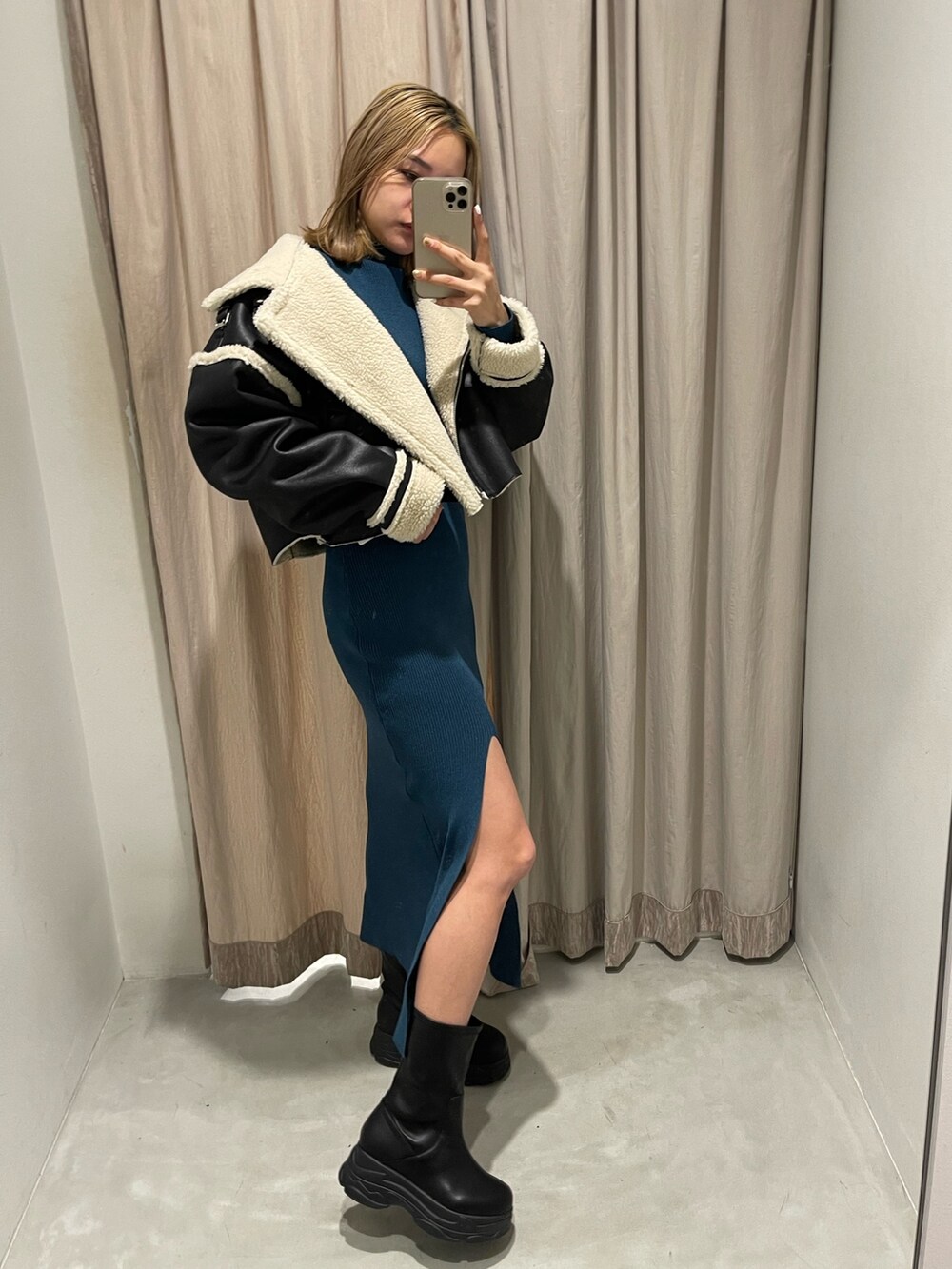 ブラック系のブルゾン、ブルー系のワンピース、ブラック系のブーツを着用したレディースの冬コーディネートの2枚目の写真