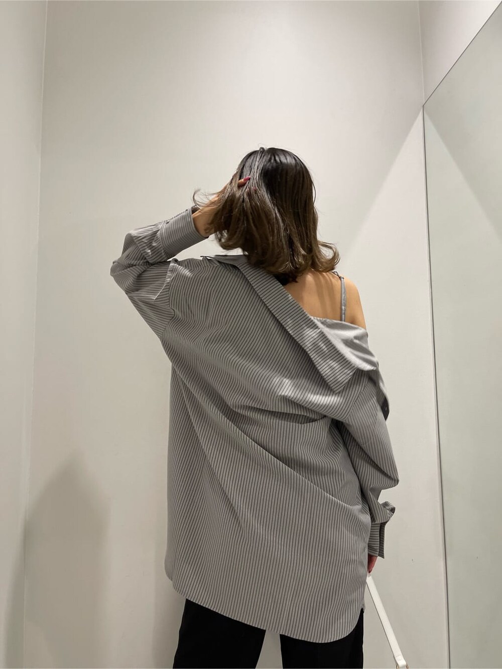 ブラック系のスラックス、ブラック系のワンピース、ホワイト系のショルダーバッグを着用したレディースの春コーディネートの7枚目の写真