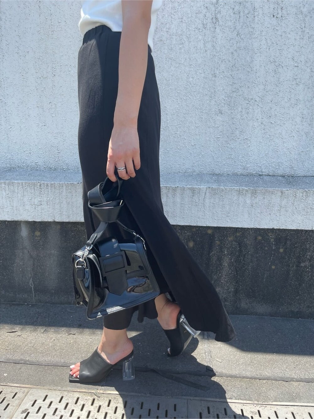 ブラック系のサンダル、ブラック系のショルダーバッグ、ホワイト系のTシャツ/カットソーを着用したレディースの夏コーディネートの7枚目の写真