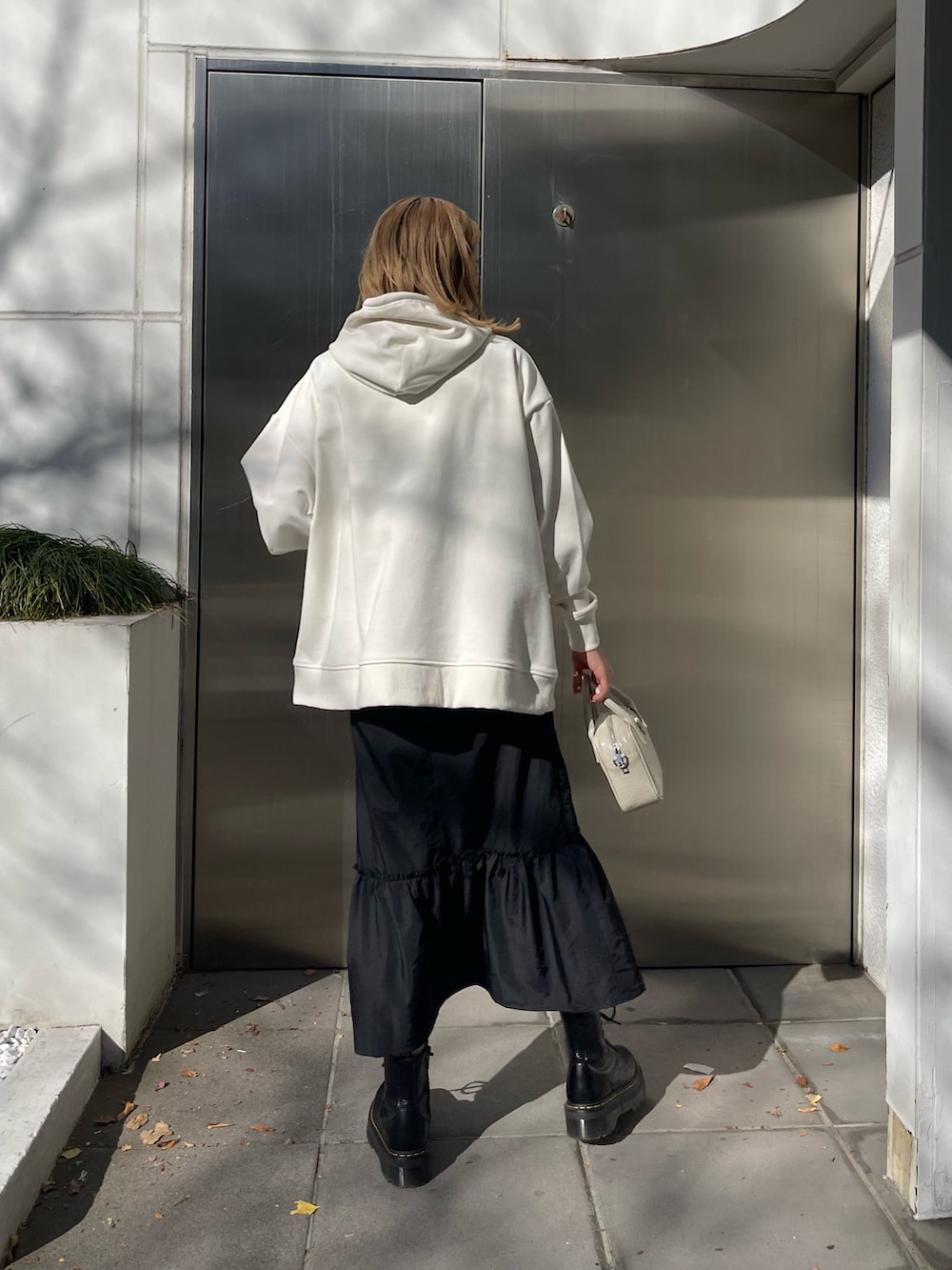 ホワイト系のパーカー、ホワイト系のショルダーバッグ、ブラック系のブーツを着用したレディースの冬コーディネートの2枚目の写真