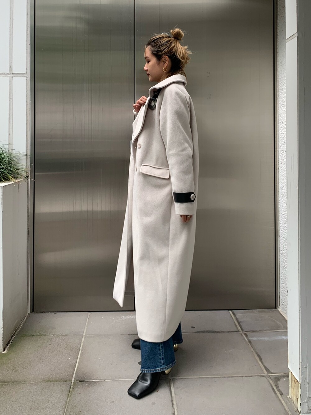 ホワイト系のその他アウター、ブラック系のニット/セーター、ブルー系のデニムパンツを着用したレディースの秋コーディネートの2枚目の写真