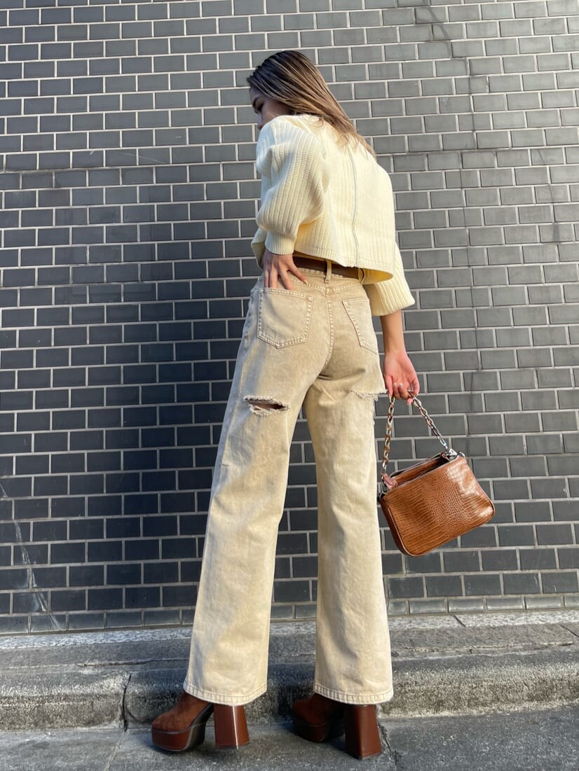 ベージュ系のデニムパンツ、ブラウン系のショルダーバッグ、ホワイト系のニット/セーターを着用したレディースの冬コーディネートの2枚目の写真