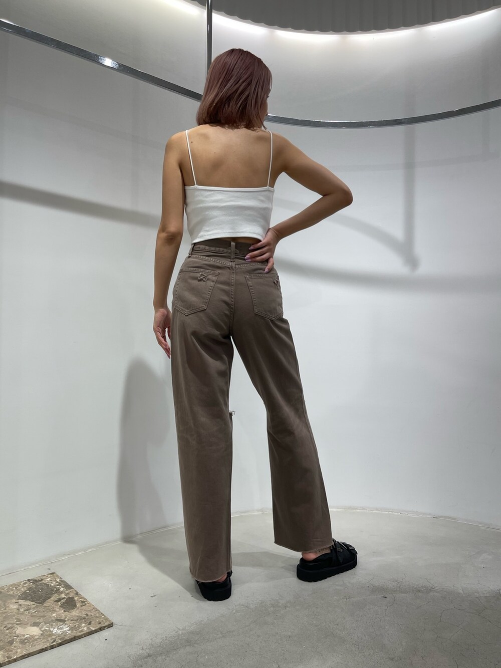 ブラック系のサンダル、ブラウン系のデニムパンツ、ホワイト系のキャミソールを着用したレディースの夏コーディネートの3枚目の写真