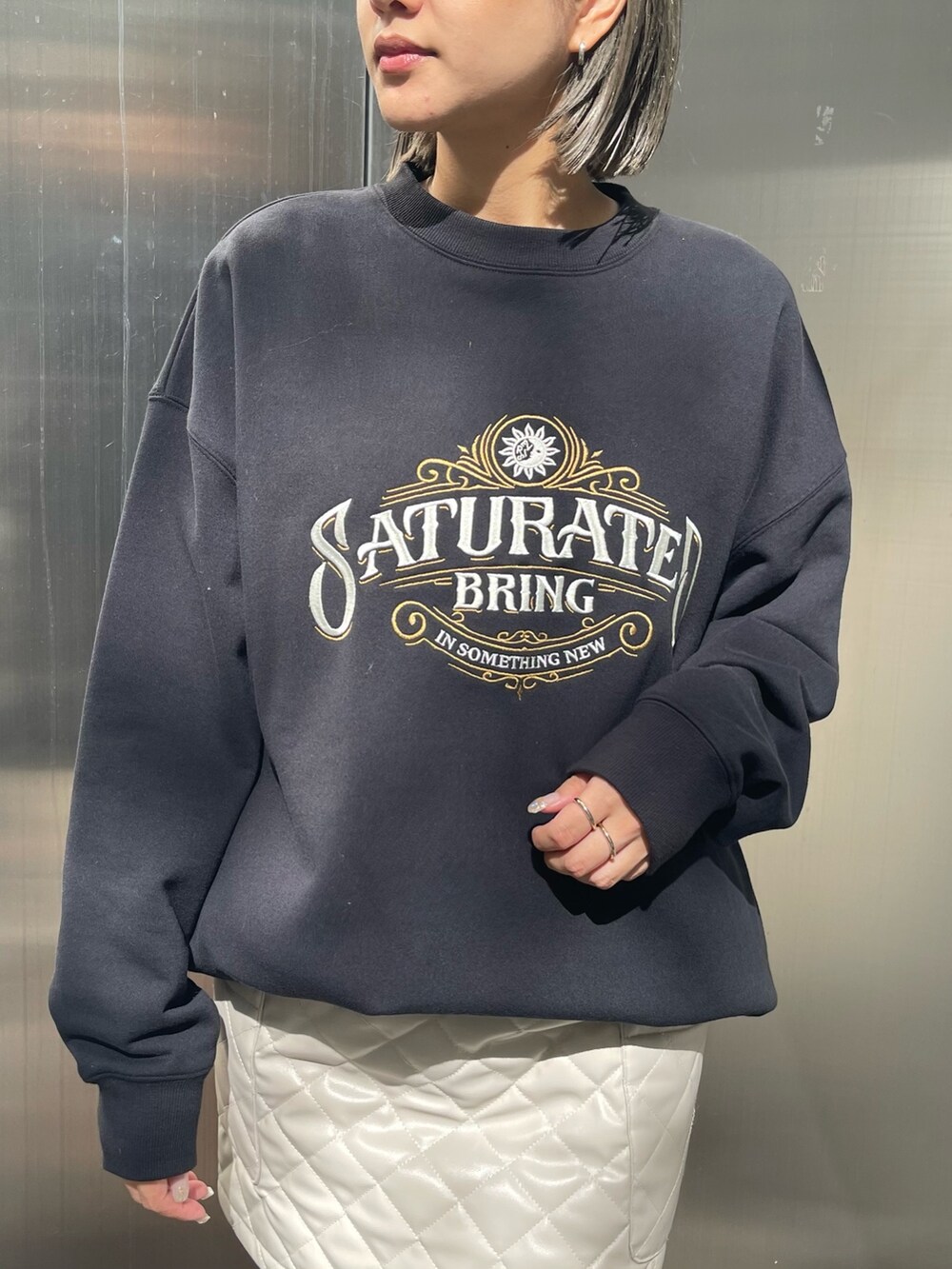 ブラック系のスウェット、ホワイト系のスカート、ブラック系のブーツを着用したレディースの秋コーディネートの4枚目の写真