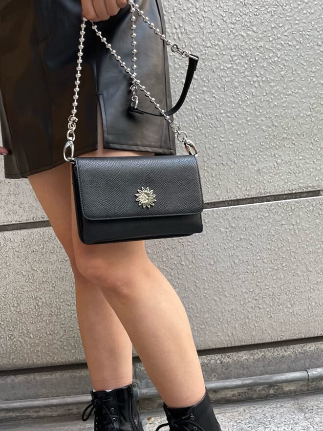 ブラック系のブーツ、ブラック系のショルダーバッグ、ブラック系のスカートを着用したレディースの秋コーディネートの6枚目の写真