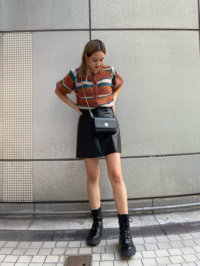 ブラック系のブーツ、ブラック系のショルダーバッグ、ブラック系のスカートを着用したレディースの秋コーディネートの2枚目の写真