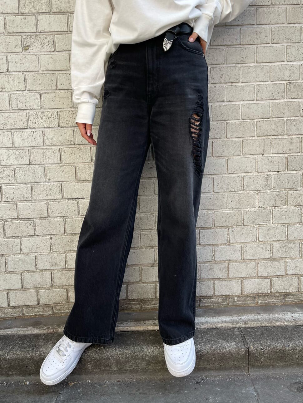 ブラック系のデニムパンツ、ホワイト系のTシャツ/カットソー、ホワイト系のベルトを着用したレディースの冬コーディネートの4枚目の写真