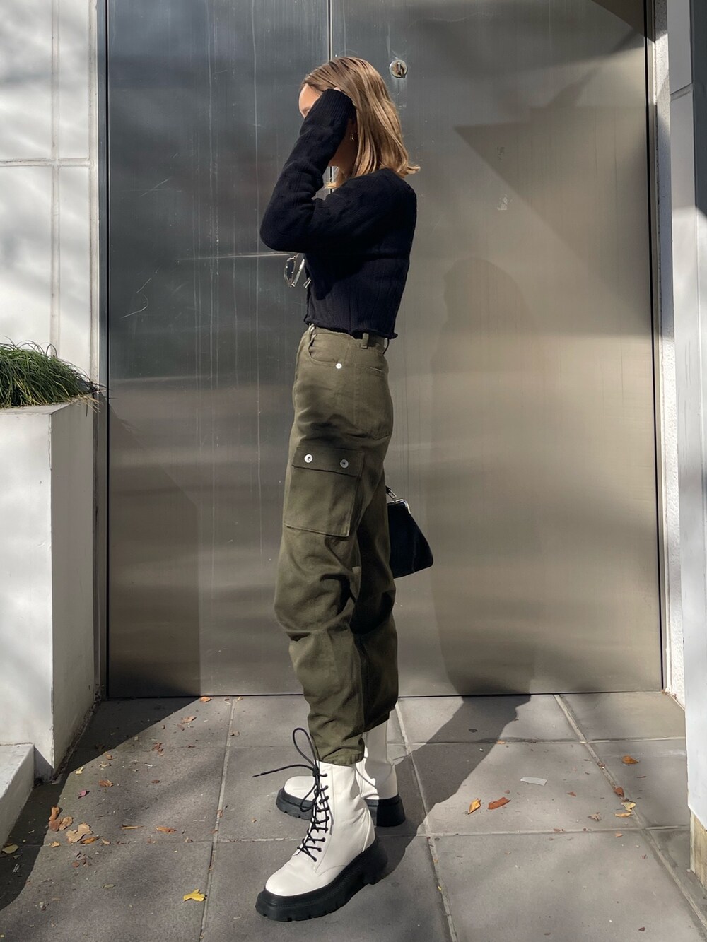 ブラック系のカーディガン/ボレロ、ブラック系のショルダーバッグ、ホワイト系のブーツを着用したレディースの冬コーディネートの2枚目の写真