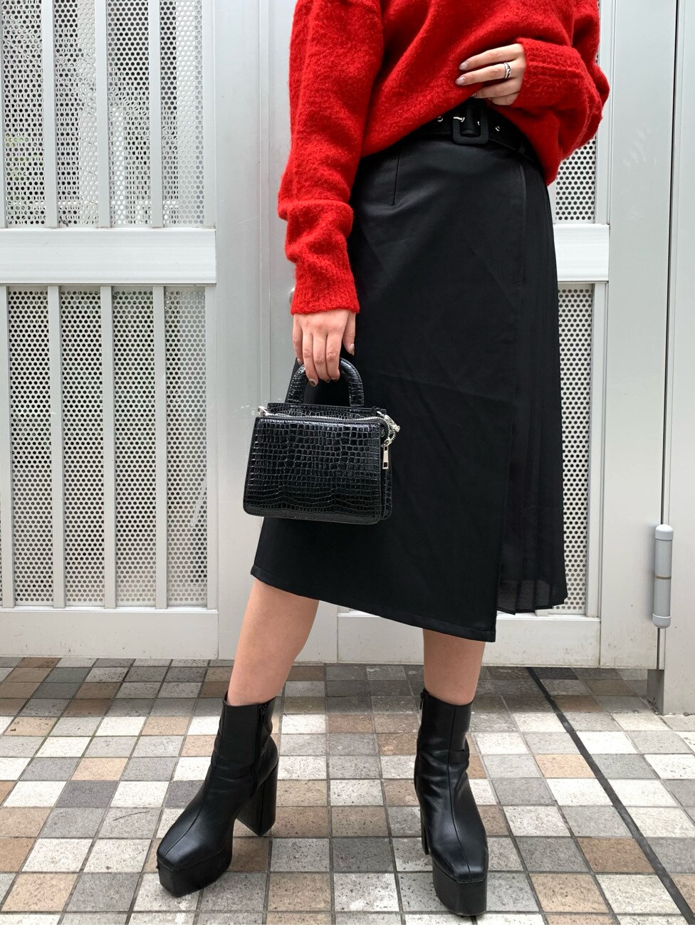 レッド系のニット/セーター、ブラック系のスカートを着用したレディースの秋コーディネートの3枚目の写真