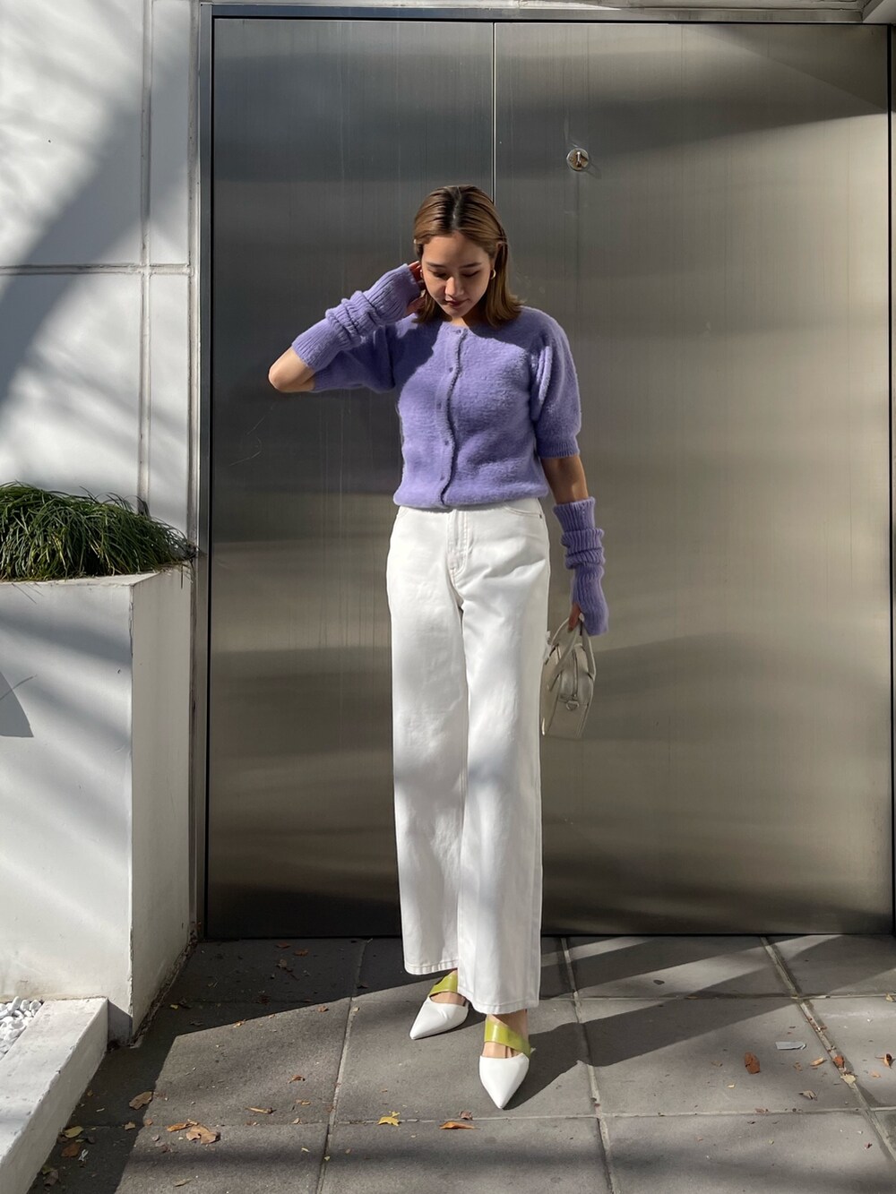 パープル系のニット/セーター、ホワイト系のデニムパンツ、ホワイト系のショルダーバッグを着用したレディースの冬コーディネートの2枚目の写真