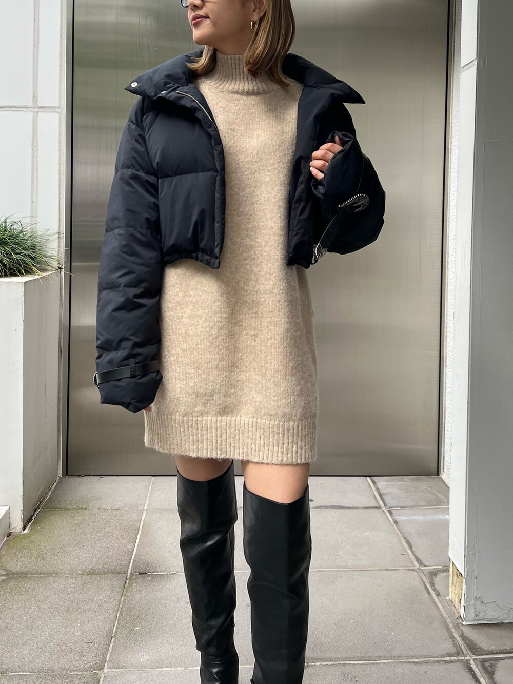 ベージュ系のワンピース、ブラック系のダウンジャケット/コート、ブラック系のブーツを着用したレディースの秋コーディネートの5枚目の写真